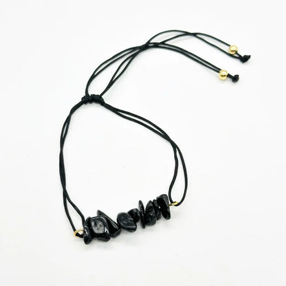 Detalle de pulsera de hilo negro con trocitos de turmalina negra